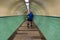 Cyclist walks his bike through tile lined underground subway pedestrian tunnel with lights