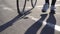 cyclist walks next to road bike on asphalt Bicycle wheel athlete s legs close-up