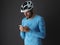 The cyclist wears a blue long sleeve and a white helmet, uses a smartphone.