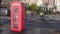 Cyclists in a cycle lane go past a British phone box in the rain