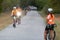 Cyclists riding north on trail as another cyclist watches, editorial.