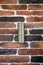Cylindrical steel light fixture is fixed to an old brick wall. The colored bricks are varnished. Vintage decor.