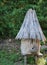 Cylindrical wooden beehive with thatched roof in old style