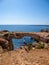 Cyprus - A girl standing in front of a rocky arch