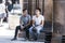 CYPRUS, NICOSIA - JUNE 10, 2019: Two handsome guys sitting together on wooden bench next to ancient columns of the historic