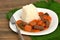 Czech meal from beef meat and carrot with rice on white plate on green gunny cloteh on dark wooden background