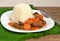 Czech meal from beef meat and carrot with rice on white plate on green gunny cloth on dark wooden background