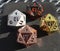 D20 twenty-sided golden silver copper and black metallic die dice on foam background in bright sunshine - 1 on top face