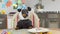 Dachshund dog in hoodie with funny panda ears, wearing festive hat is sitting at table in front of birthday cake with