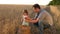 Dad is an agronomist and small child is playing with grain in a bag on wheat field. father farmer plays with little son