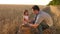 Dad is an agronomist and small child is playing with grain in a bag on wheat field. father farmer plays with little son
