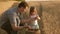 Dad is an agronomist and small child is playing with grain in a bag on wheat field. father farmer plays with little son