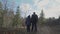 Dad with backpack holds his son by hand and slowly walks through forest