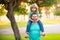 Dad and child having fun outdoors. Father giving son ride on back in park. Portrait of happy father giving son piggyback