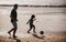 Dad and child playing outdoor, silhouette on sunset. Father and son play soccer or football on the beach on summer