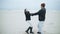 Dad with daughter holding hands to swing around on the beach