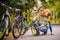 Dad and daughter inspect wheel of children`s teenage bicycle on the autumn path of the park