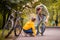 Dad and daughter inspect wheel of children`s teenage bicycle on the autumn path of the park