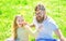 Dad and daughter sits on grass at grassplot, green background. Daddys princess concept. Child and father posing with