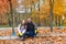 Dad and daughter are sitting in the park on the curb after harvesting the fallen leaves.
