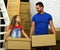 Dad and daughter stand by pile of cardboard boxes.