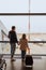 dad and daughter with a suitcase stands by the window at the airport.