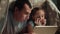 dad and daughter under the blanket with a digital tablet. night kid dream online video games at concept. dad and