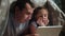 Dad and daughter under the blanket with night a digital tablet. Kid dream online video games at concept. Dad and