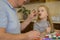 dad feeds honey from a spoon to a sick child at home, who is distracted from the disease by drawing. The father suspects