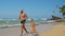 Dad and little kid run along exotic ocean coast against sky