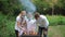 Dad, mom and children fry meat on skewers on the grill. Family in medical masks at a picnic in the Park. Outdoor recreation during