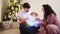 dad, mom and little daughter by Christmas tree and play with garland and embrace