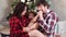 dad, mom and little daughter in red plaid pajamas playing at the Christmas tree