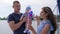 Dad and mom play with son at lake, woman entertains baby with help pinwheel on loch,