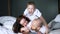 Dad, mom and son in identical white T-shirts have fun on bed closeup indoors, happy moments