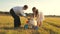 Dad and Mom teach daughter to ride a bike. Mother and father play with small child on lawn. kid learns to ride bicycle