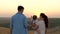 Dad, Mom is walking with her daughter showing child sunset. Happy family, mother, father and daughter are walking in the