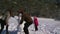 Dad, mother and little daughter make a snowman in the meadow near the forest.