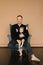 Dad with one-year-old daughter in black clothes sitting on a gray chair on a beige background. Fatherly love. Father`s day