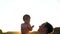 Dad plays with little baby in highlights of sunset on beach during high summer season. Parent throws child up and laughs