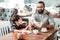 Dad reading book for his son waiting for order in cafeteria