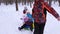 Dad rolls baby and mom on snow saucer running in winter snowy forest and laugh. Man and woman with their daughters had