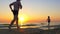 Dad runs after the child along the sea coast at sunset.