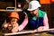 Dad shows his boy how to make diy in wooden workshop using hammer and nail. Father and son use carpenter toolsl. Little