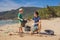 Dad and son in gloves cleaning up the beach pick up plastic bags that pollute sea. Natural education of children