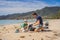 Dad and son in gloves cleaning up the beach pick up plastic bags that pollute sea. Natural education of children