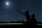 Dad and son sit on the grass at night and look at the night sky