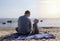Dad and son are sitting on the beach and chatting. A boy with a father on the background of the sea and sunset cuddling. The