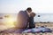 Dad and son are sitting on the beach and chatting. A boy with a father on the background of the sea and sunset cuddling. The