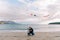 Dad, squatting down, launches a colorful kite by the sea with a little girl